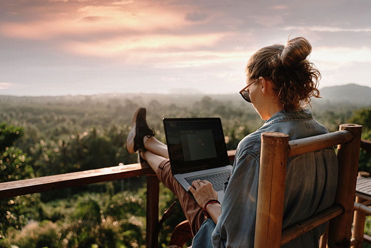 Person on laptop outside overlooking forest