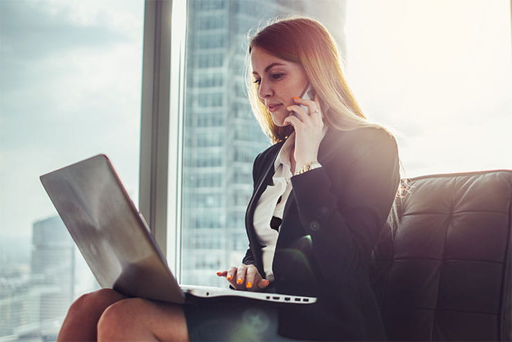 Jeune femme attendant assise dans le hall d’un bureau moderne : comment faire un suivi après une entrevue